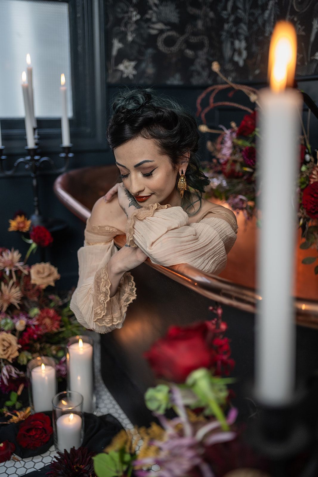 A woman is taking a bath in a bathtub surrounded by candles and flowers.
