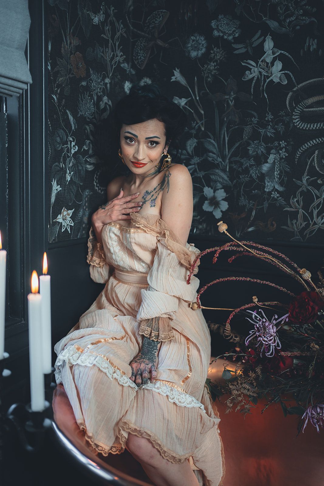 A woman in a white dress is sitting on a chair next to candles.