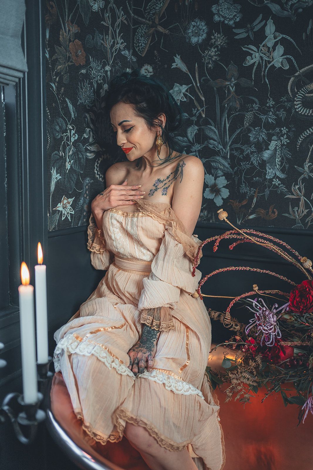 A woman in a dress is sitting in a bathtub with candles.