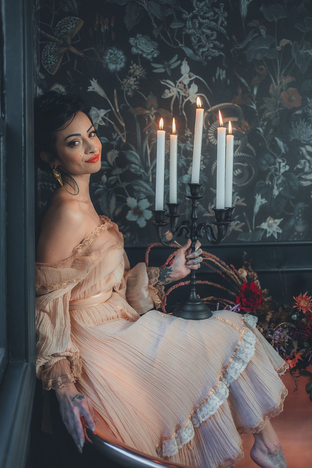 A woman in a dress is sitting in a bathtub with candles.