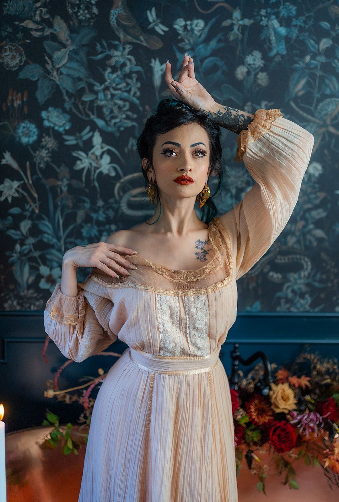 A woman in a dress is standing in front of a wall with flowers.
