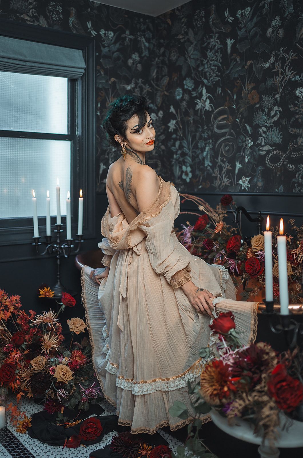 A woman in a dress is standing in a room surrounded by flowers and candles.