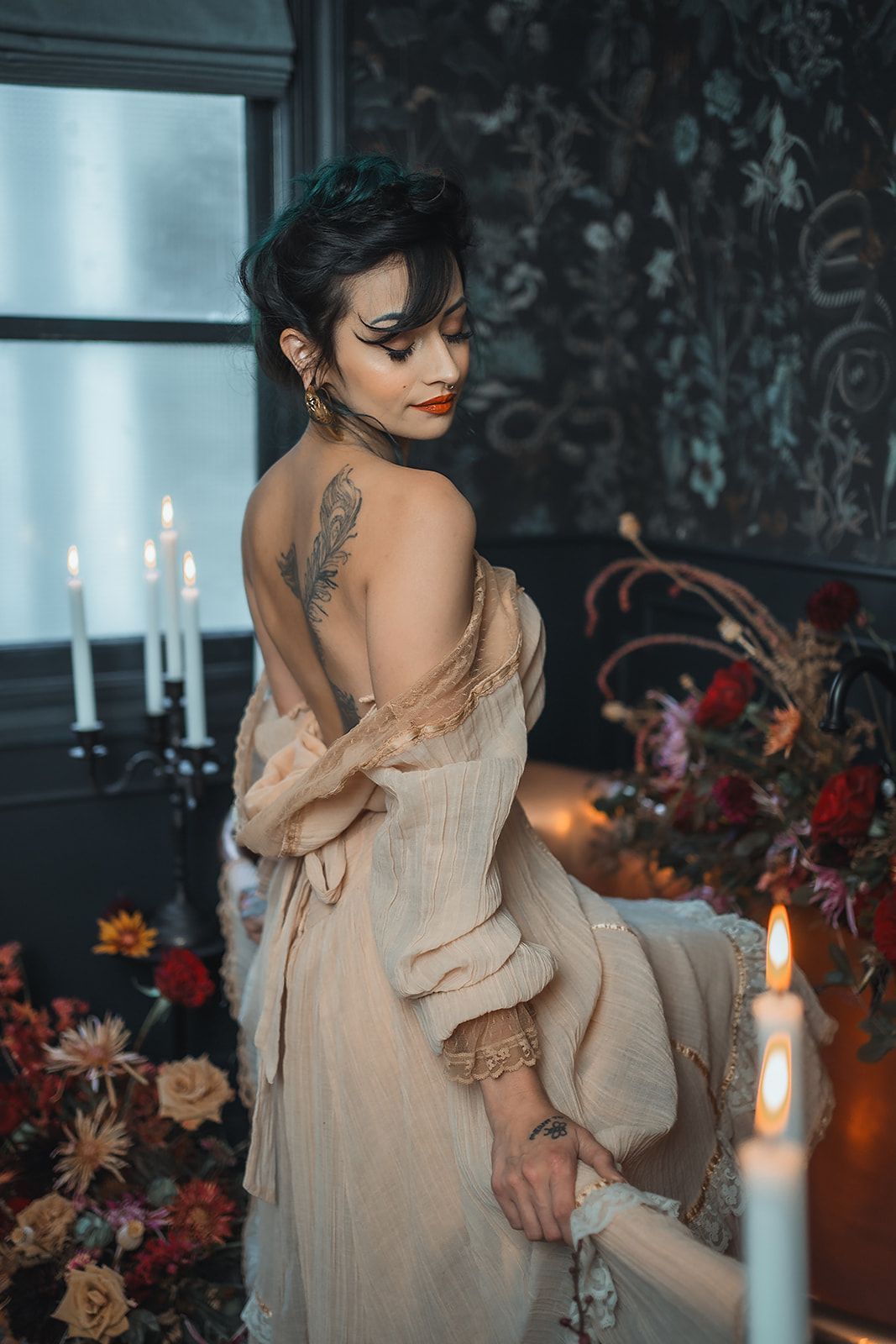 A woman in a dress is standing next to a bathtub surrounded by candles.