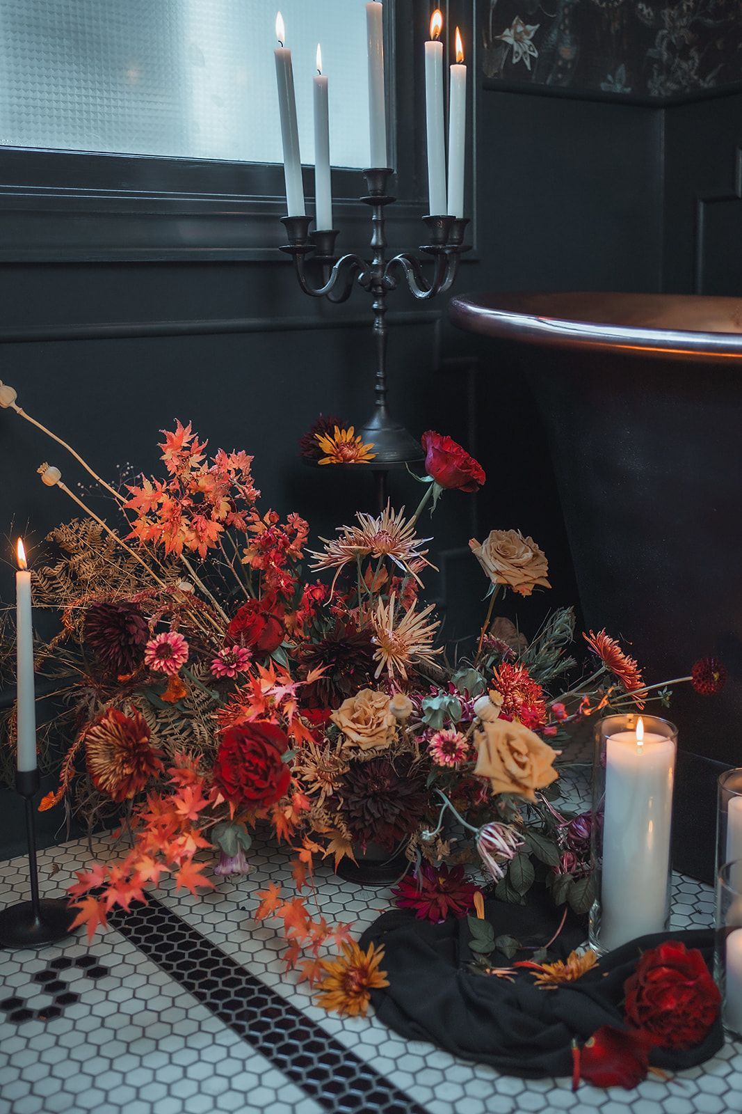 A bathtub surrounded by candles and flowers in a bathroom.