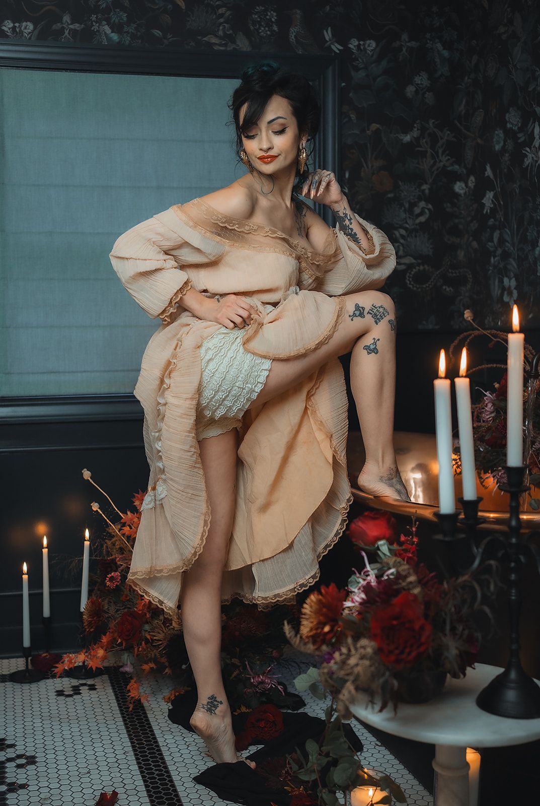 A woman in a dress is kneeling on a table with candles and flowers.
