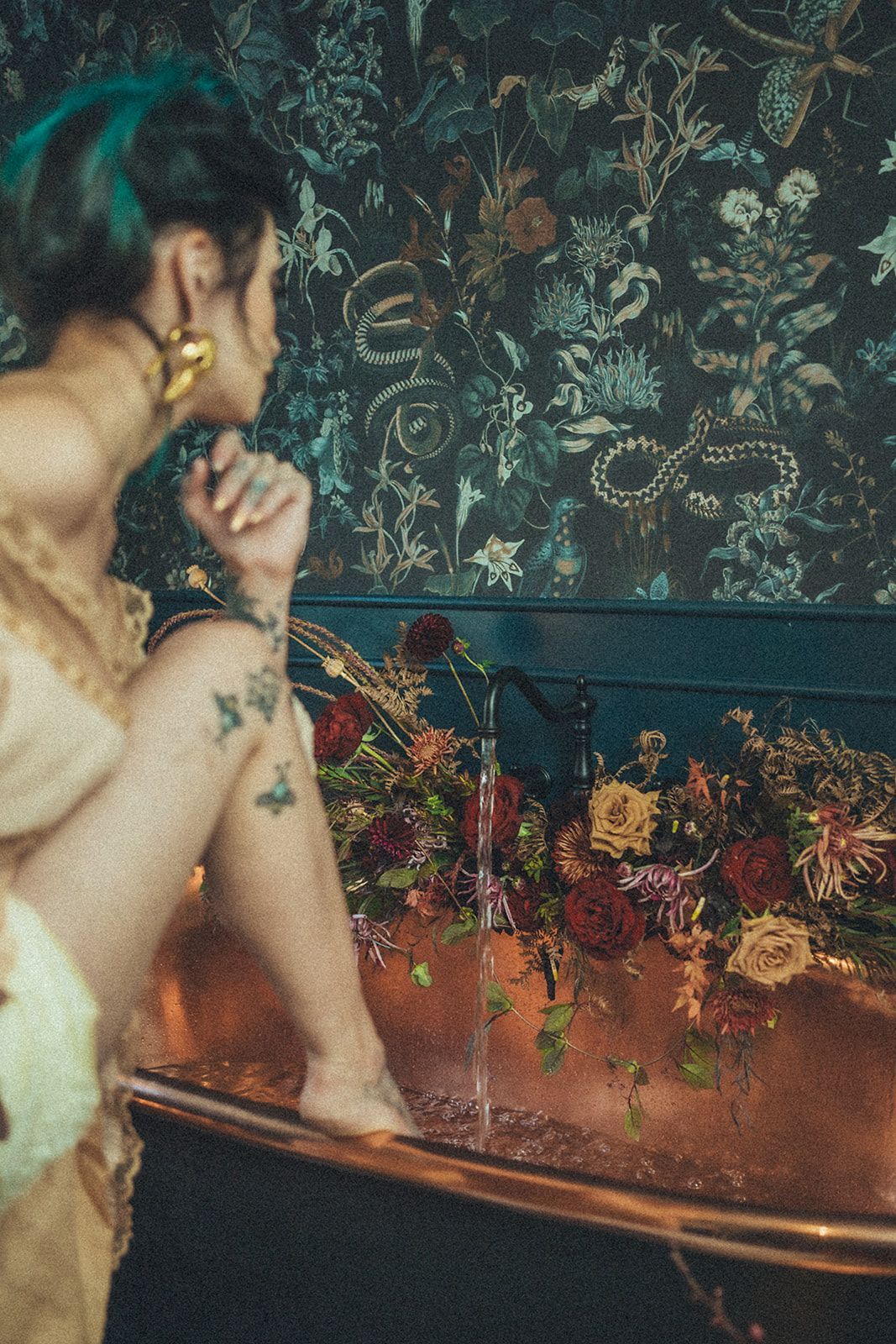 A woman is sitting in a bathtub surrounded by flowers.