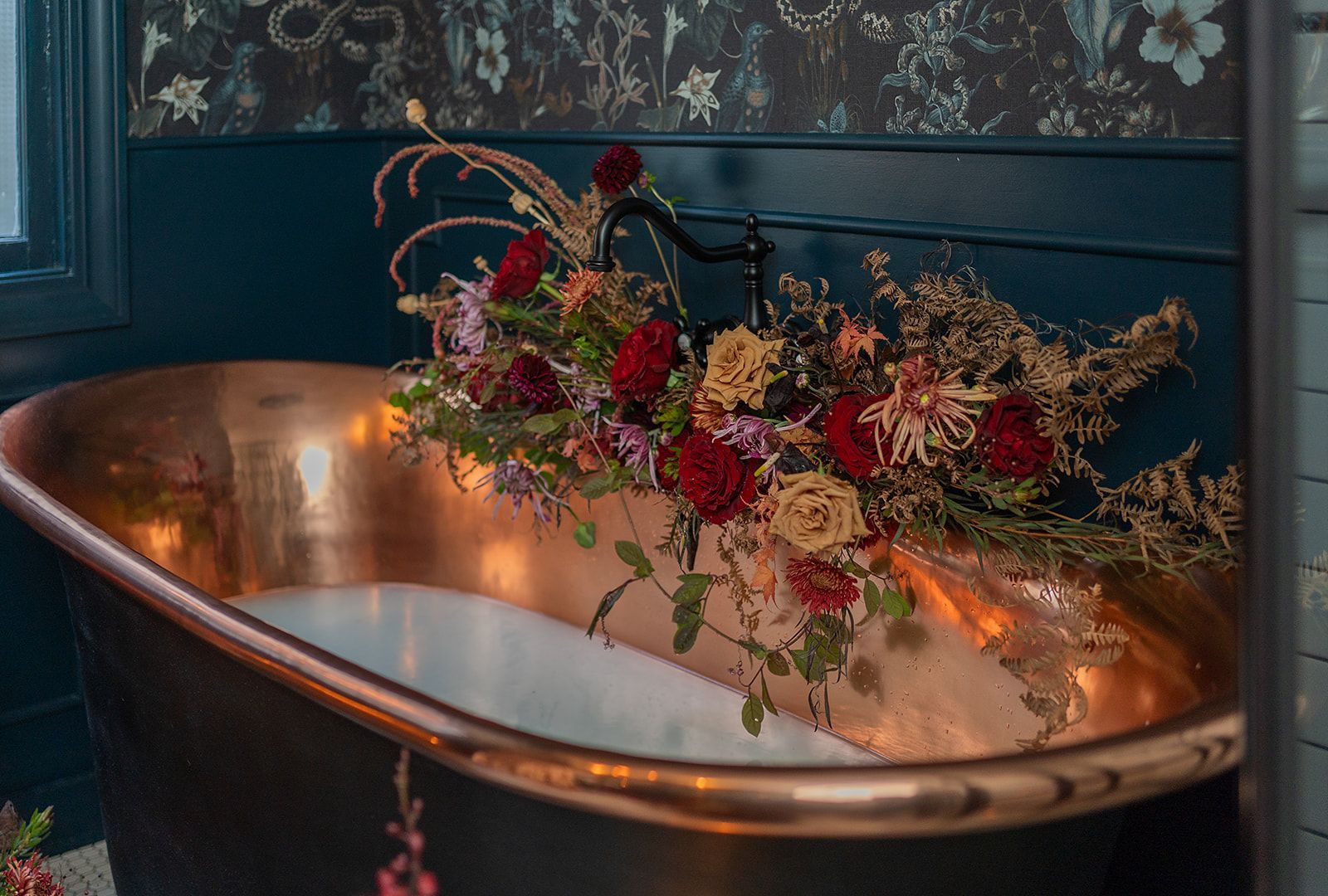 A copper bathtub filled with flowers in a bathroom.