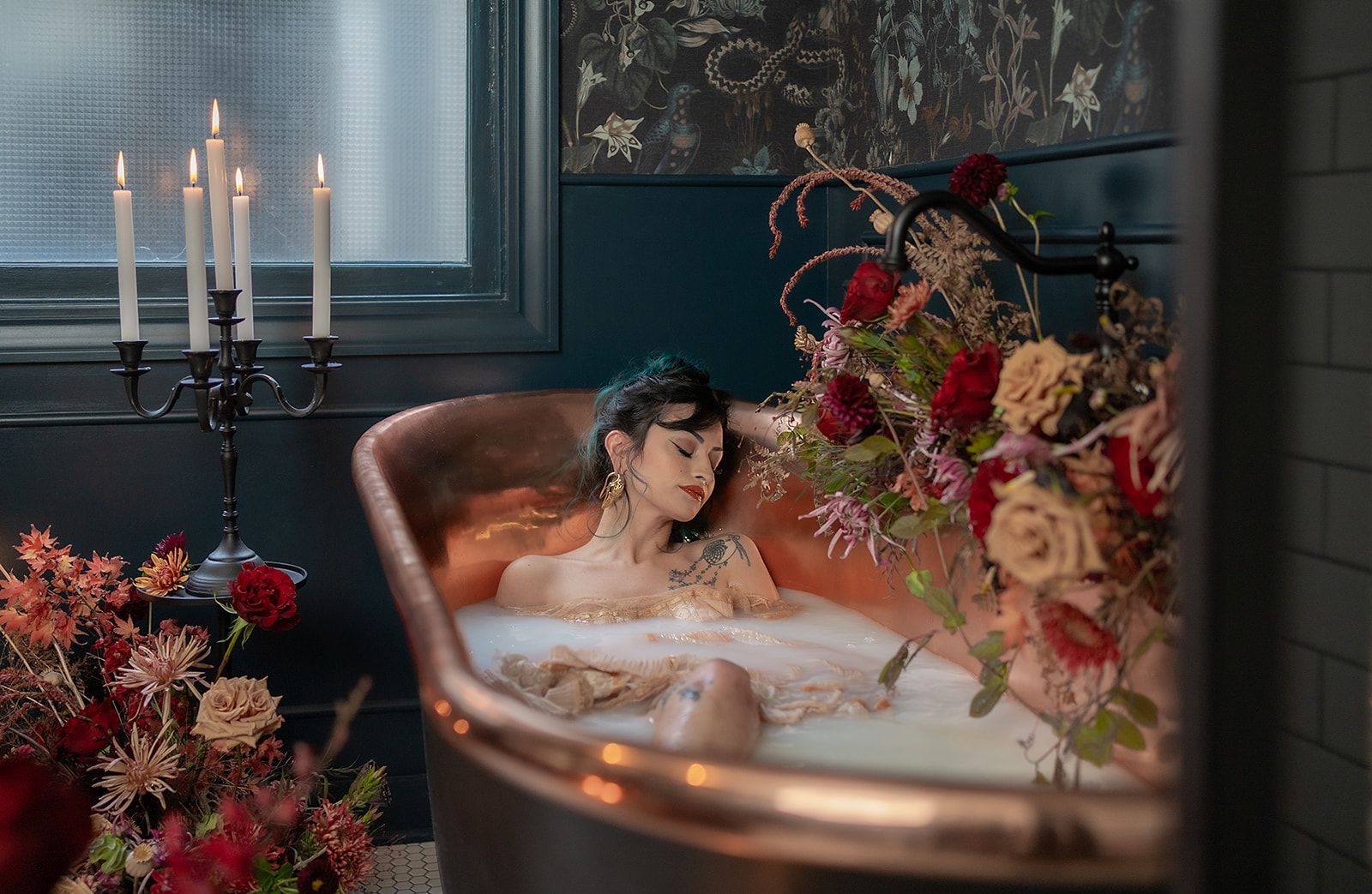 A woman is taking a bath in a bathtub surrounded by flowers and candles.