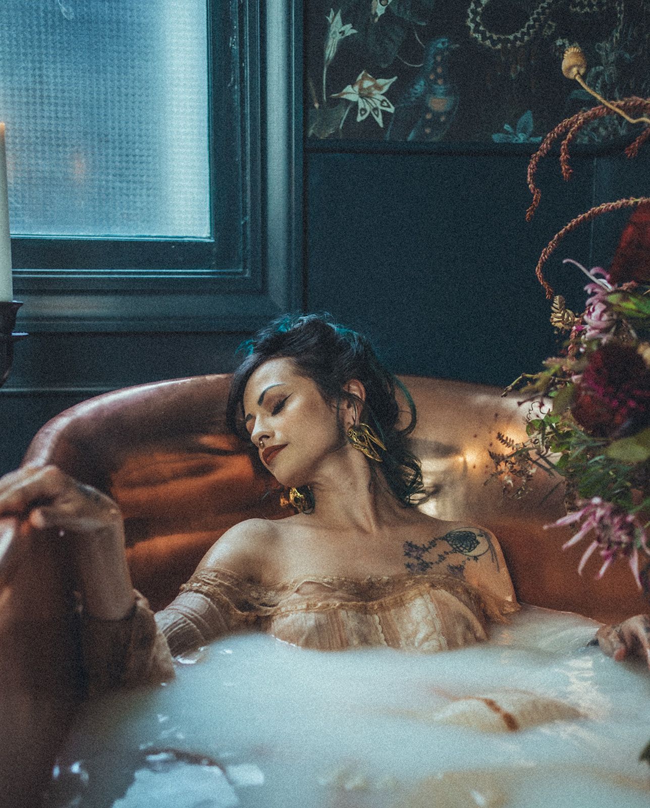 A woman is laying in a bathtub for a milk bath photo shoot in Medford, Oregon.