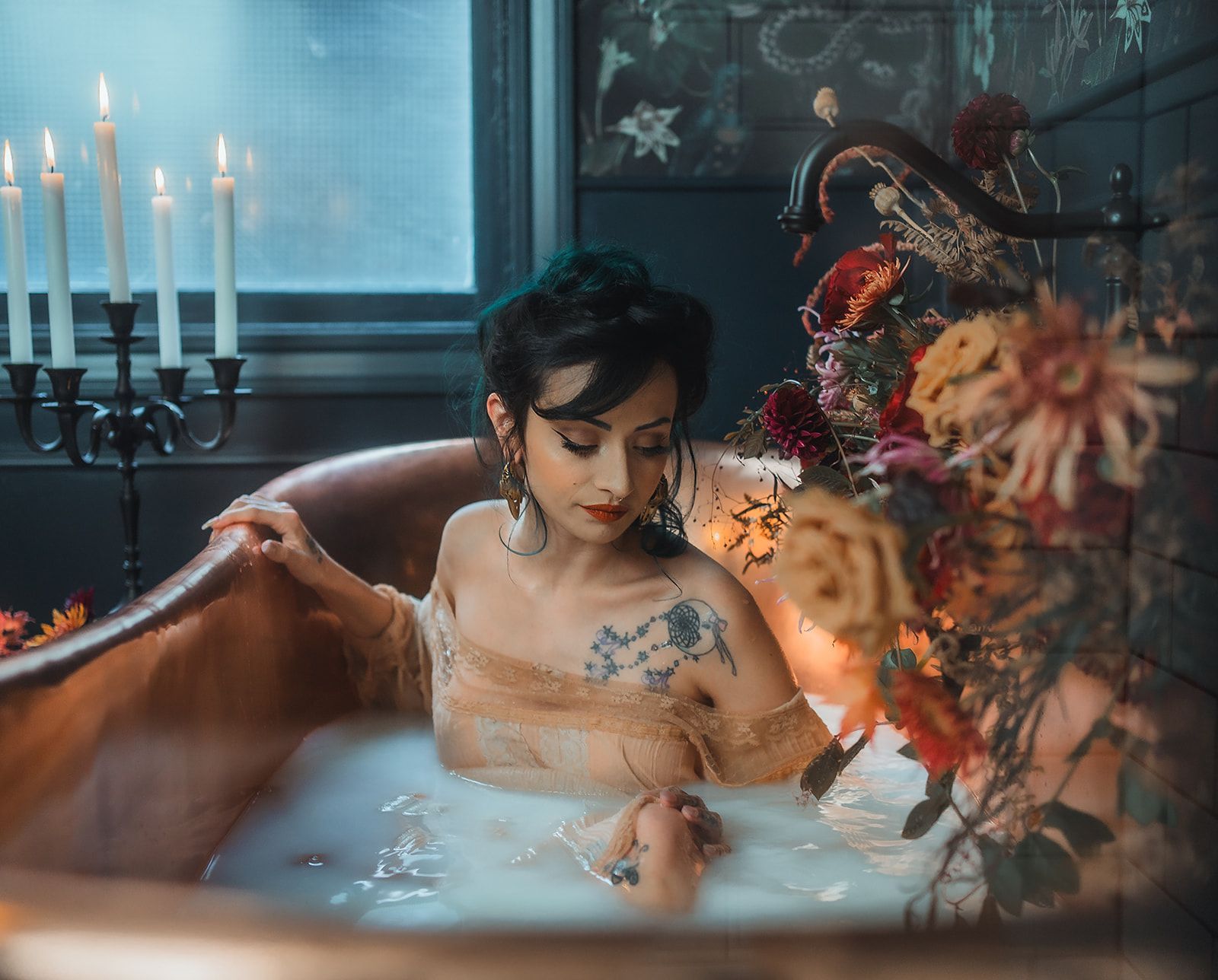 A woman sitting in a milk bath lined with flowers for a photo session in Southern Oregon.