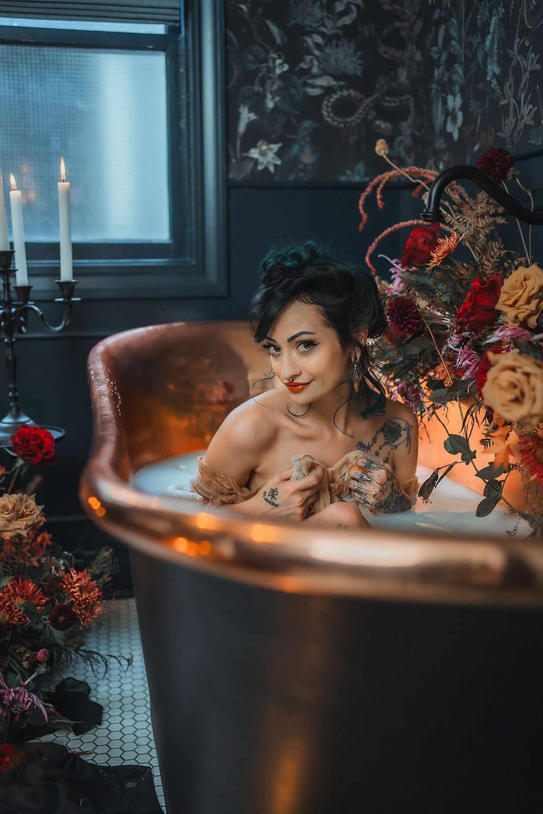 A woman is taking a milk bath in a bathtub surrounded by flowers and candles.