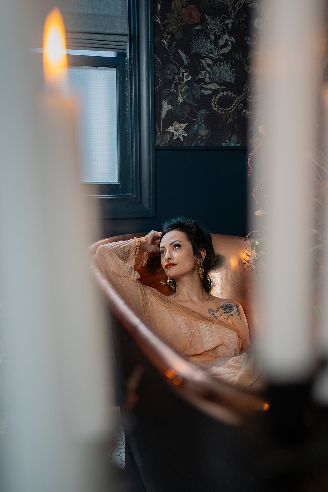A woman is laying in a bathtub next to a candle.