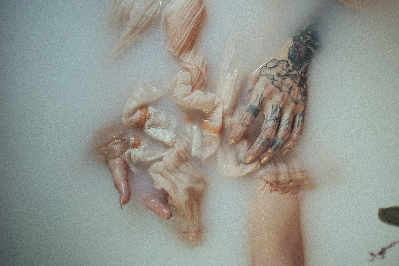 A woman with a tattoo on her arm is taking a bath in milk.