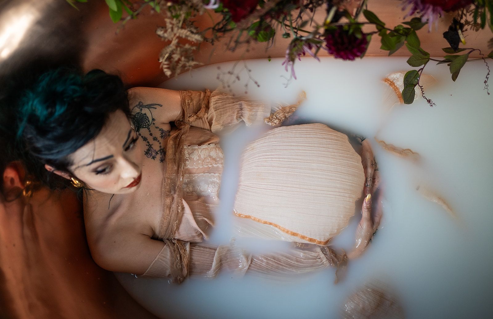 A woman is laying in a bathtub filled with milk and flowers.