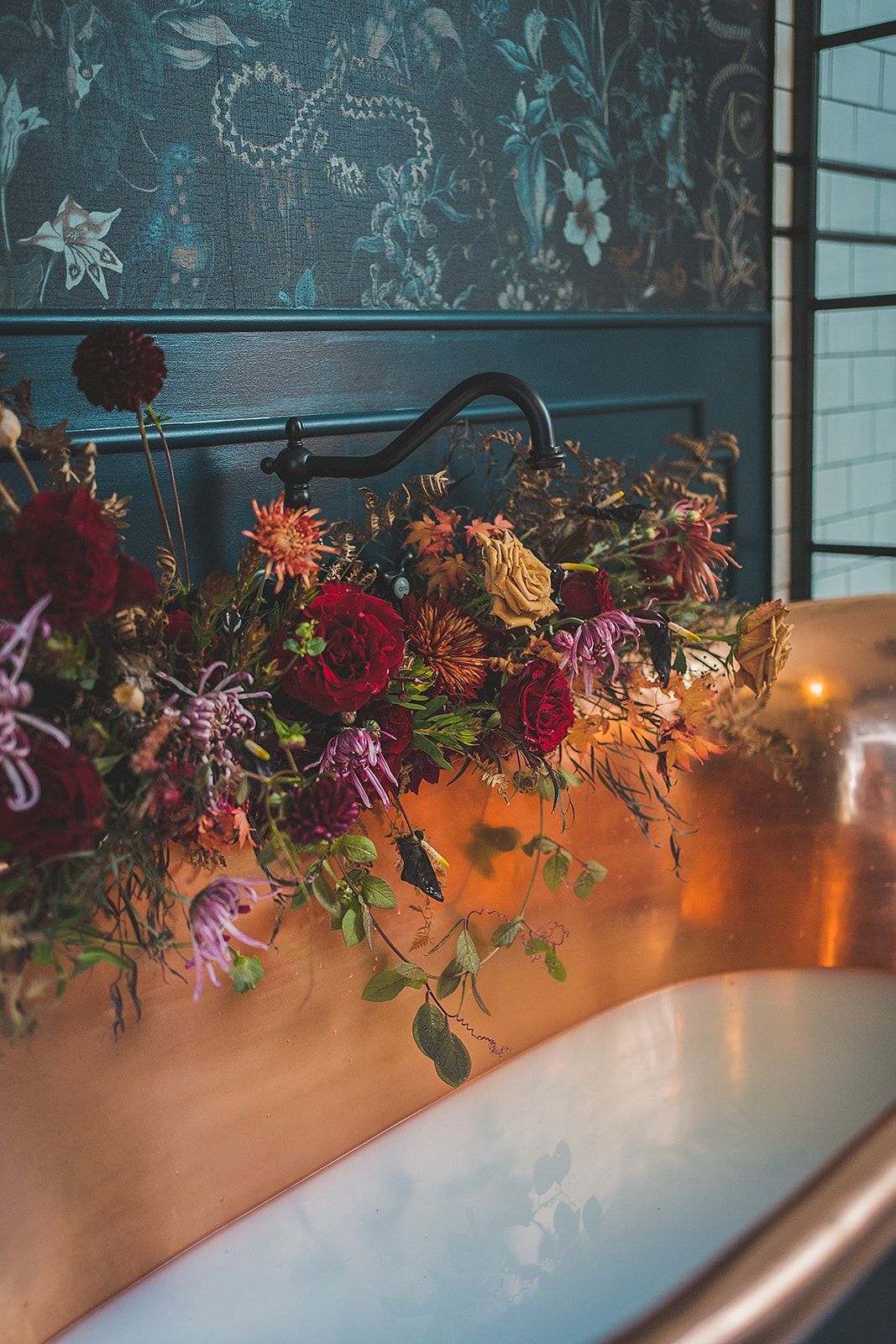 A bathtub filled with water and flowers in a bathroom.