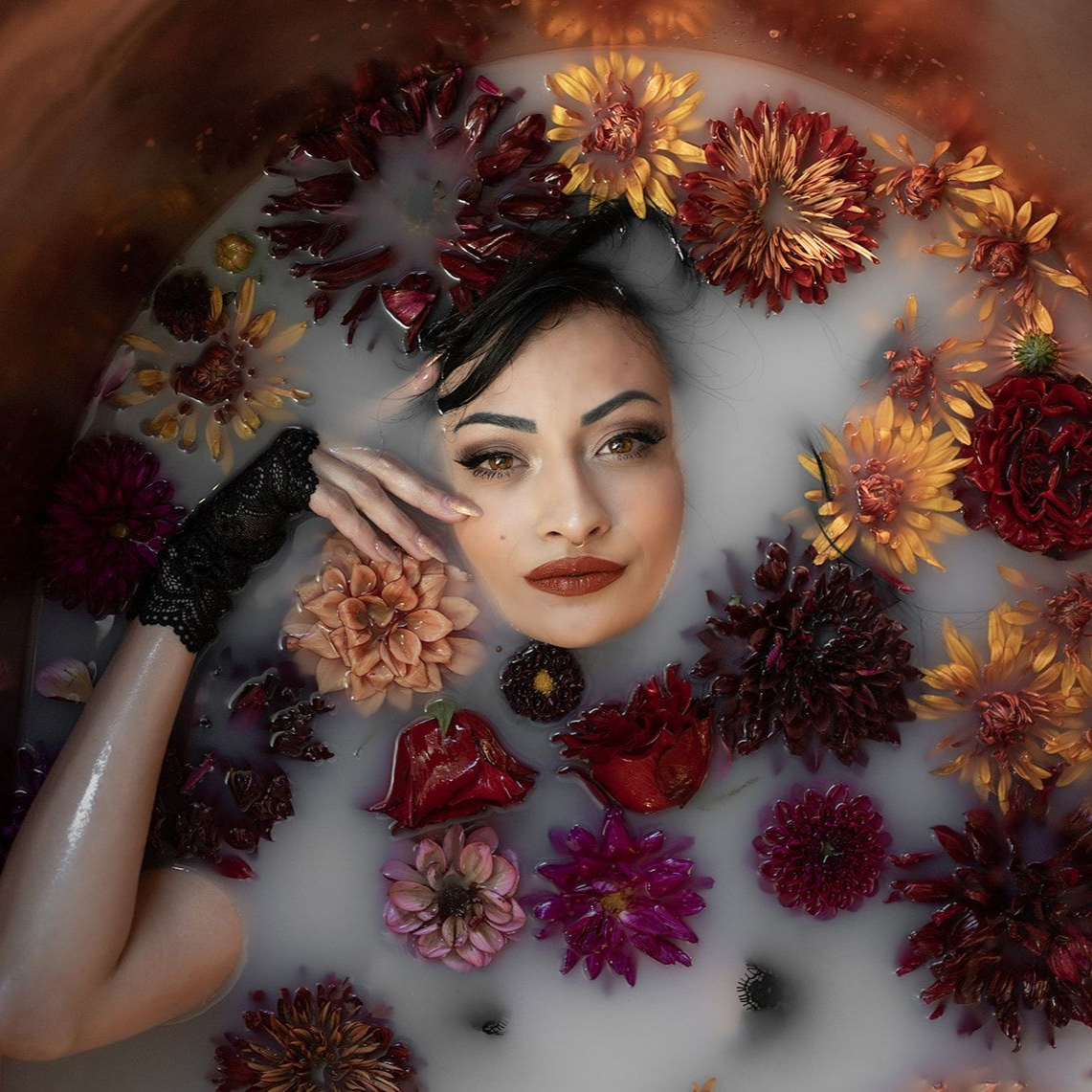 Woman surrounded by fresh flowers during a floral milk bath photography session at Milk & Peonies studio in Southern Oregon