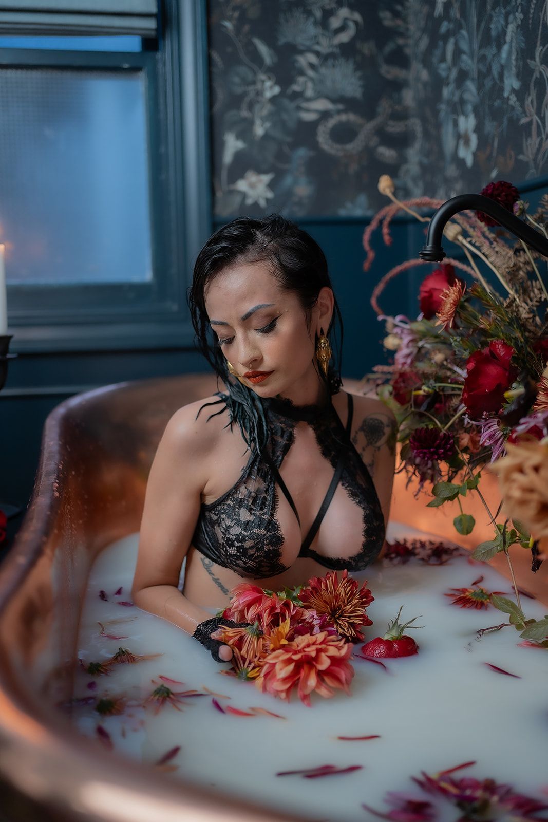 A woman is sitting in a bathtub filled with milk and flowers.