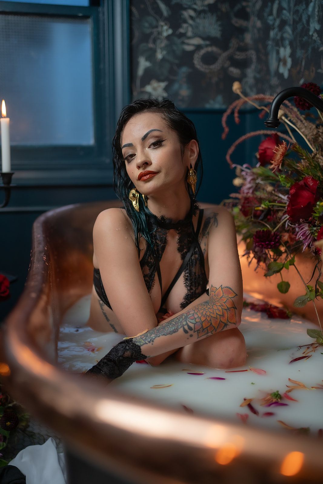 A woman is laying in a bathtub filled with milk and flowers.