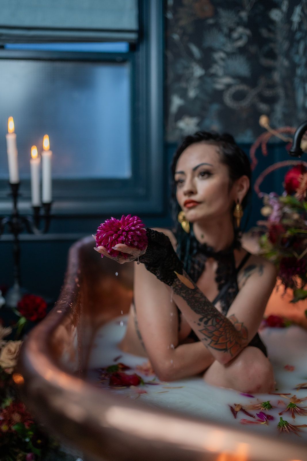 A woman is sitting in a bathtub holding a flower.