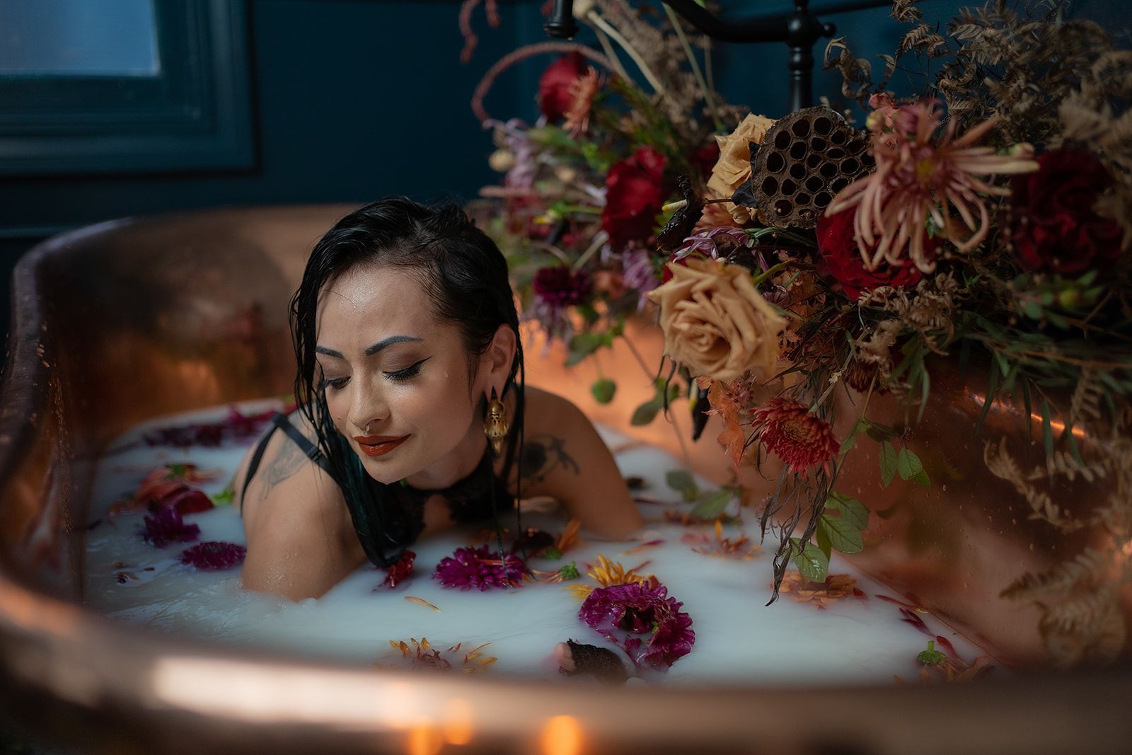 A woman is laying in a bathtub filled with milk and flowers.