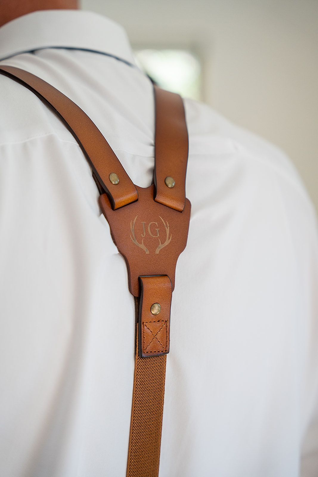 A man wearing a white shirt and brown suspenders