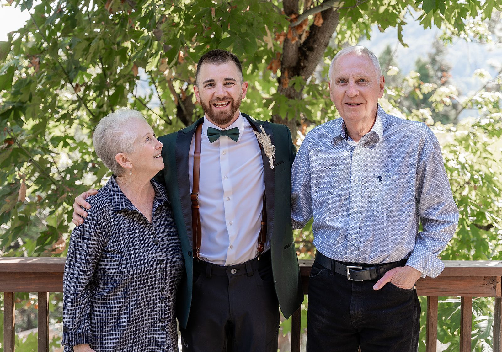 A man in a suit is posing for a picture with his parents.