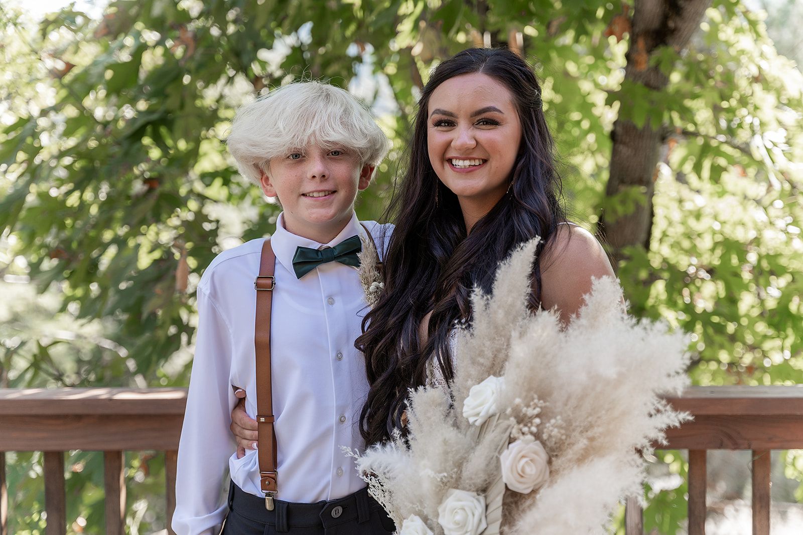 A bride and groom are posing for a picture on a deck.