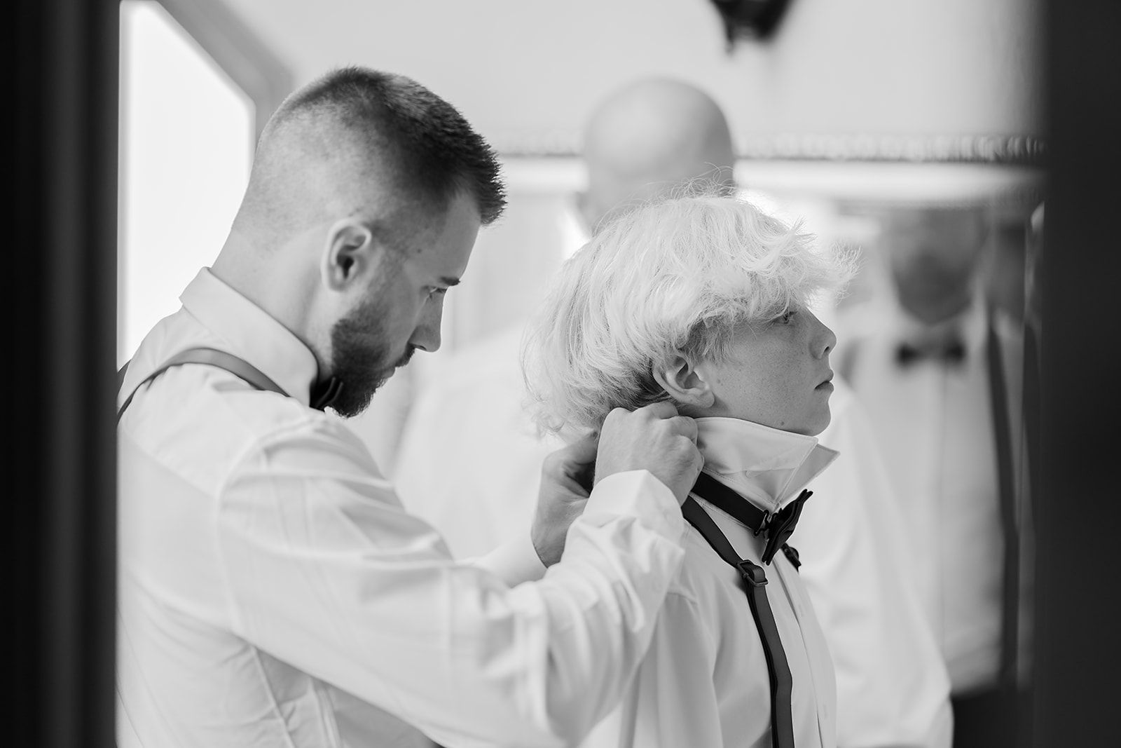 A man is helping a young boy put on a tie.