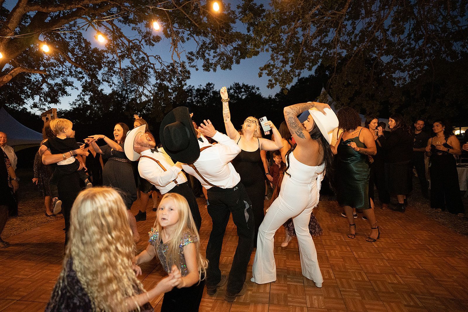 A group of people are dancing at a wedding reception.