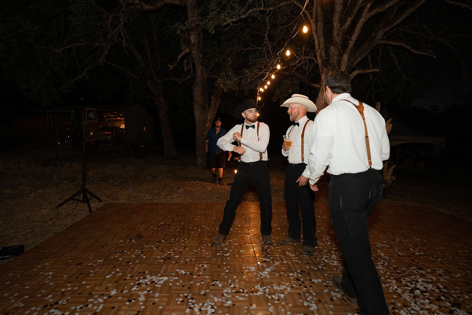 A group of men are standing on a wooden floor at night.