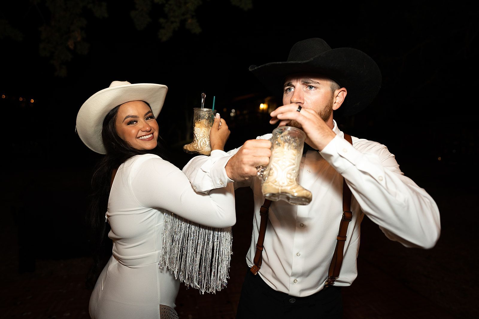 A man and a woman in cowboy hats are toasting with champagne glasses.