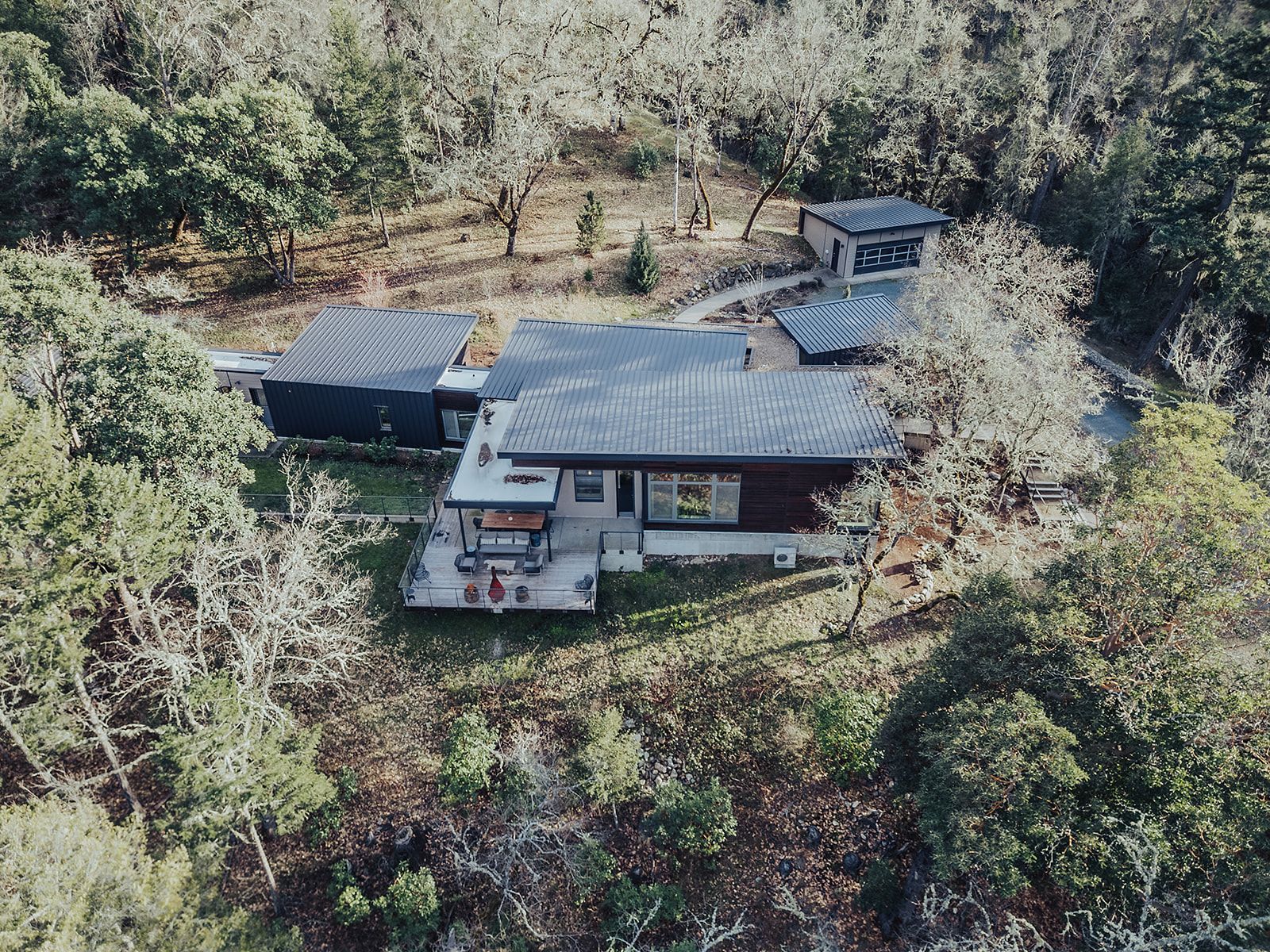 An aerial view of a house in the middle of a forest.