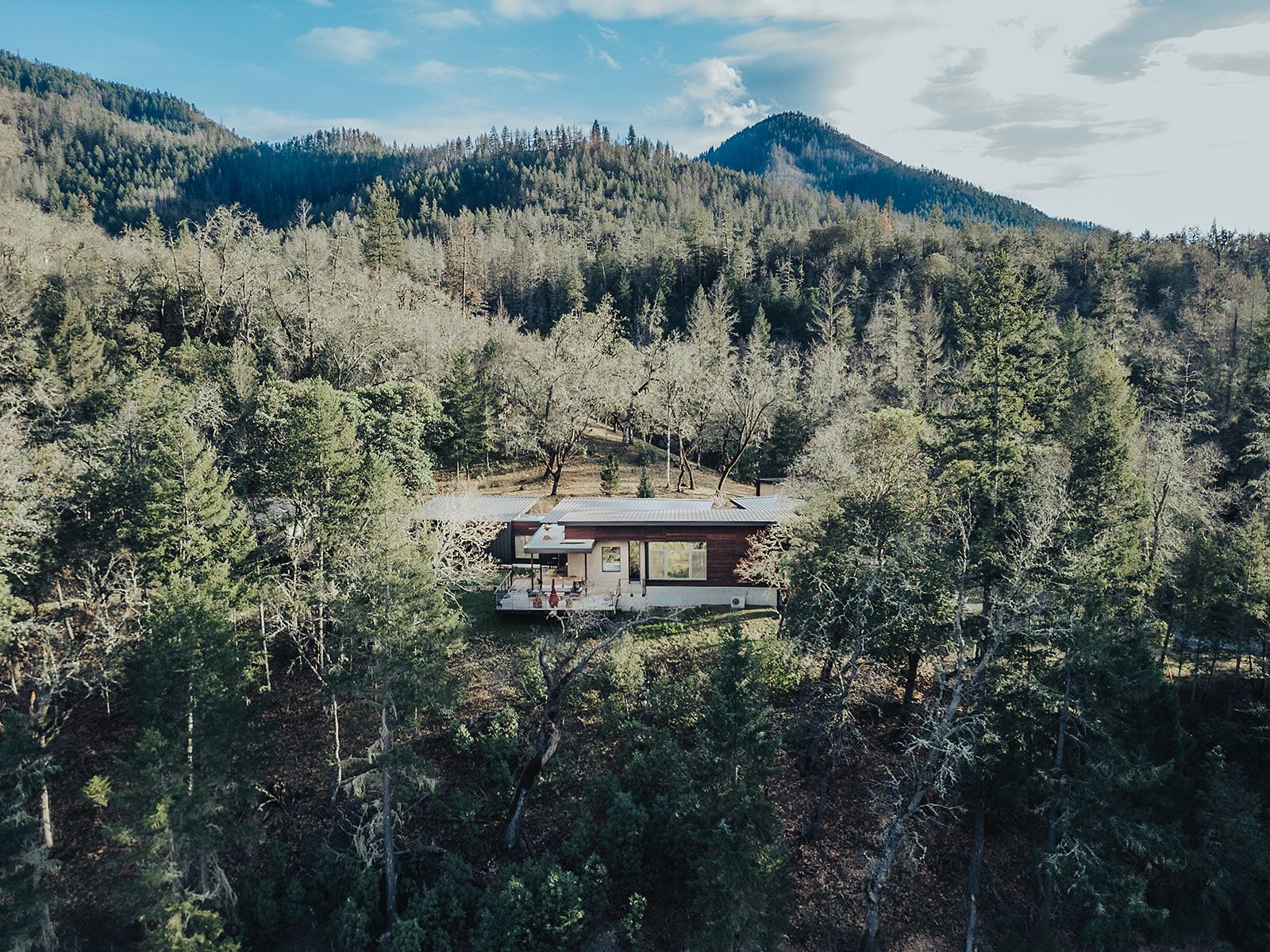 An aerial view of a house in the middle of a forest