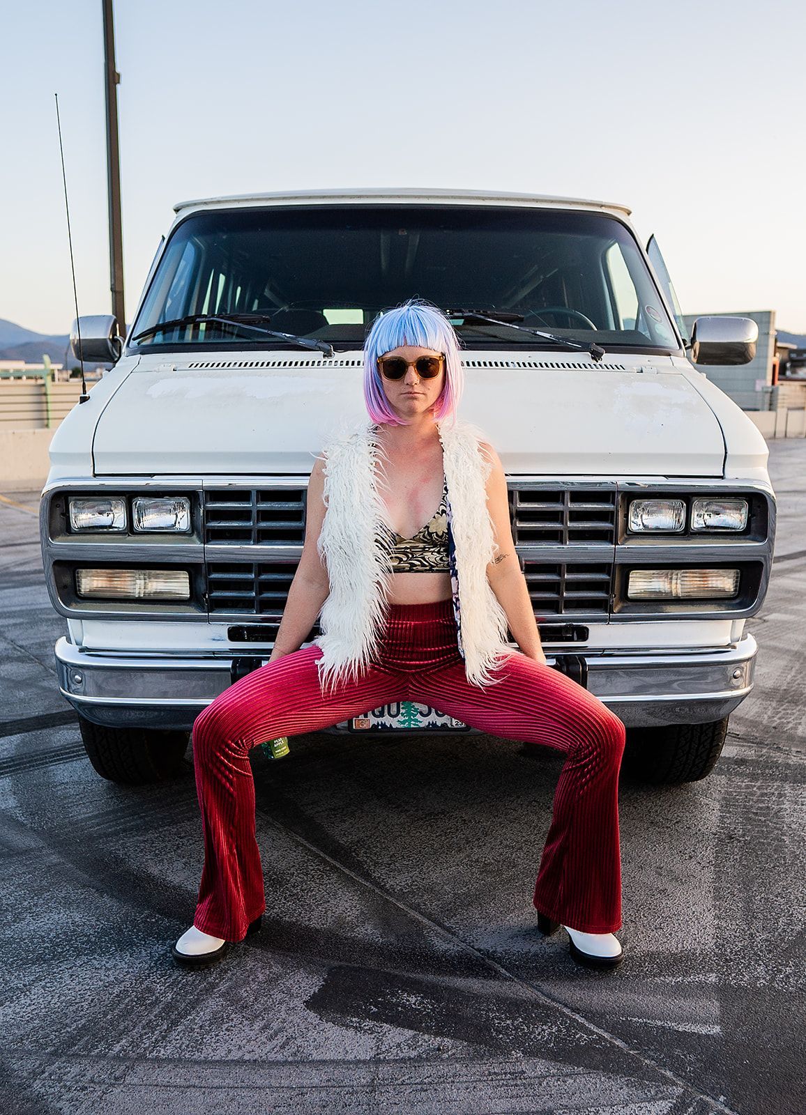 A woman is squatting in front of a white van.