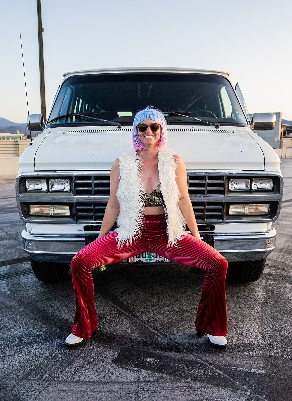 A woman is squatting in front of a white van.