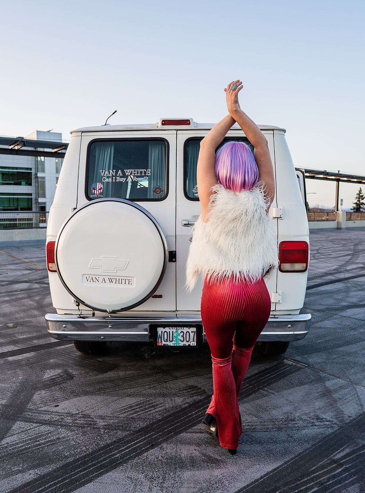 A woman with pink hair is standing in front of a white van.
