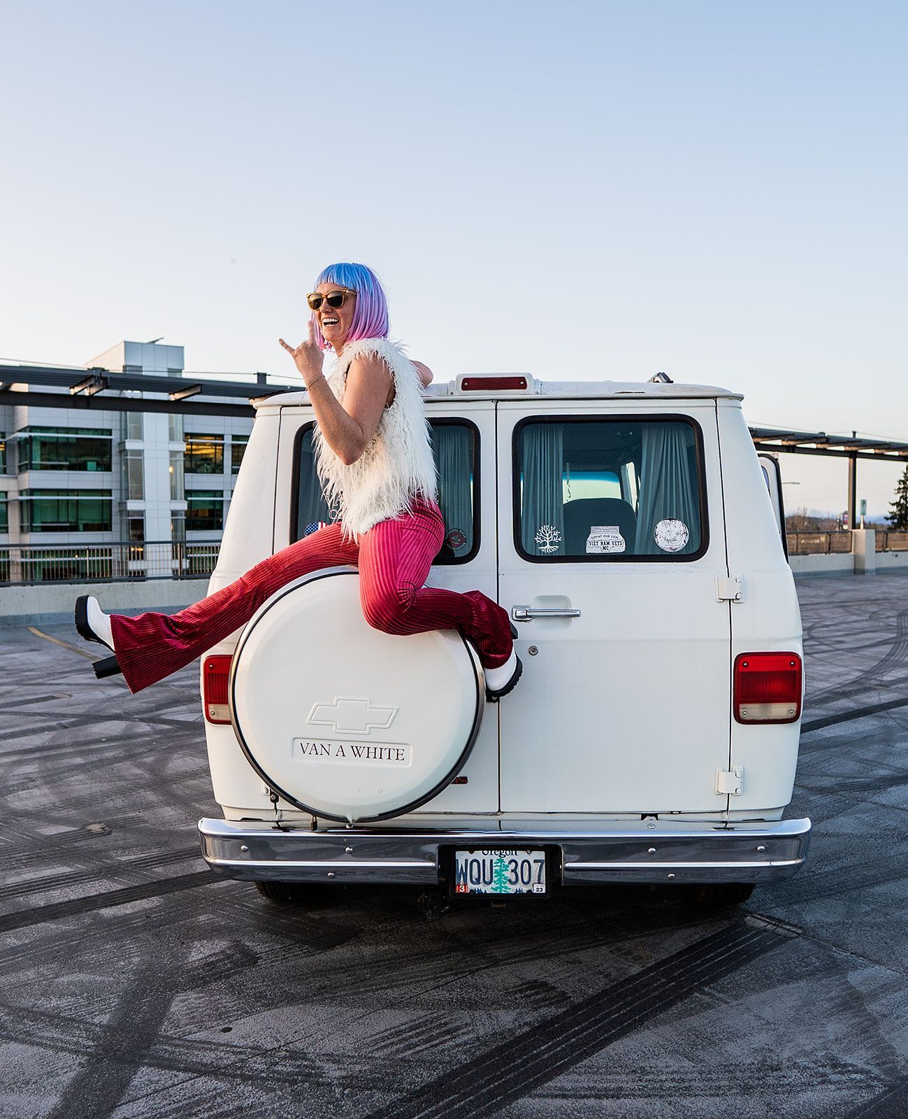 A woman is sitting on the back of a white van.