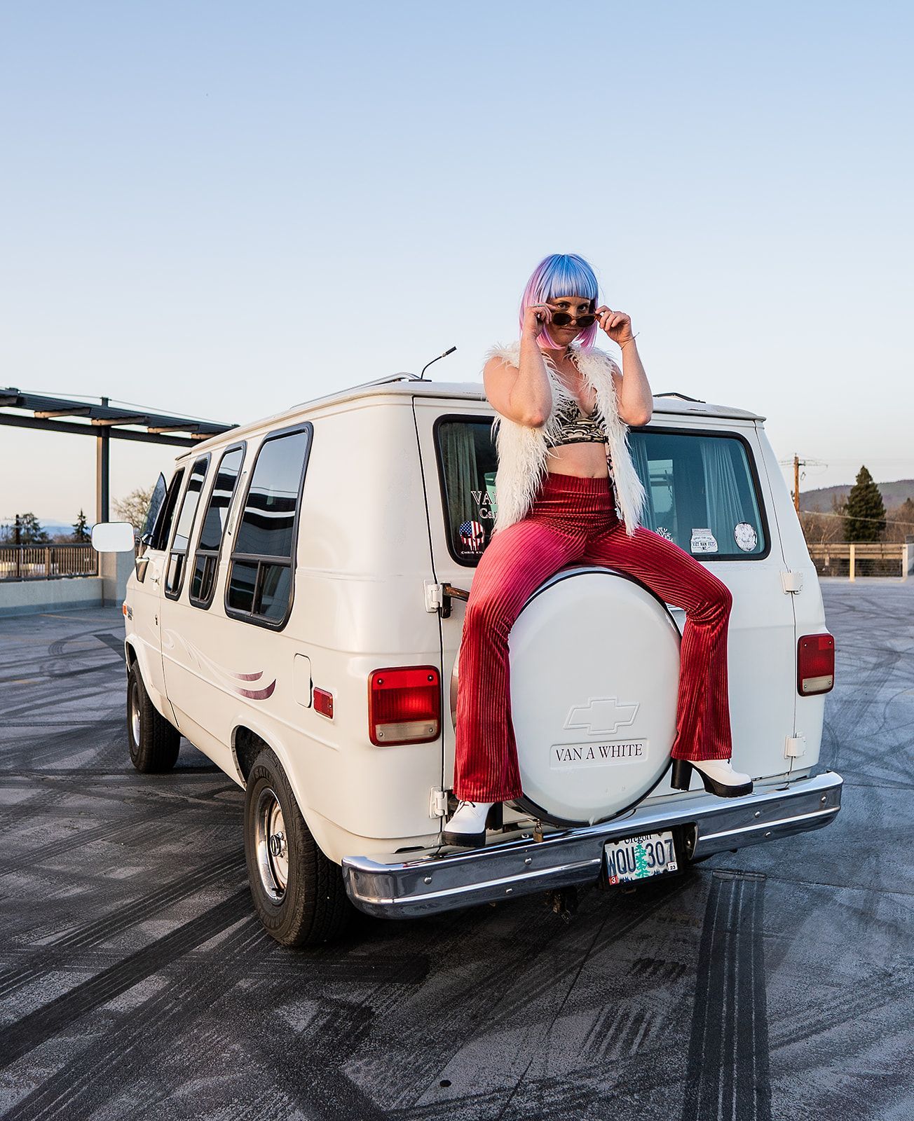 A woman is sitting on the back of a white van.