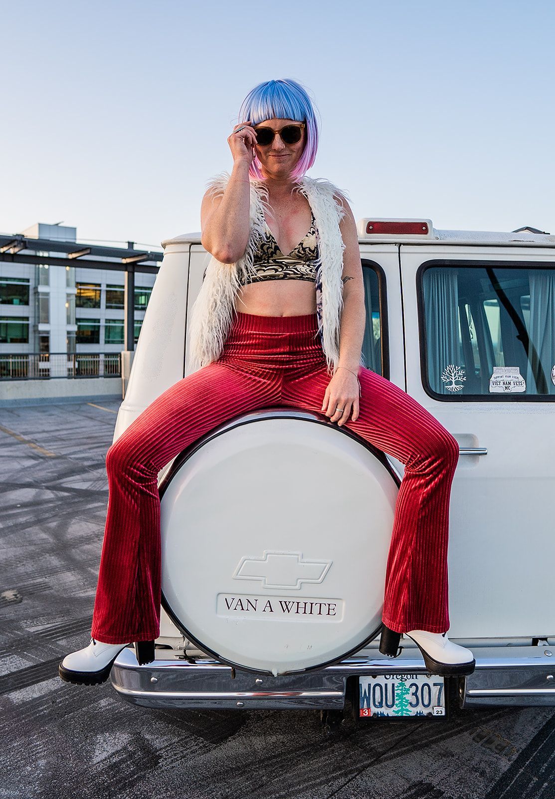 A woman is sitting on the back of a white van.