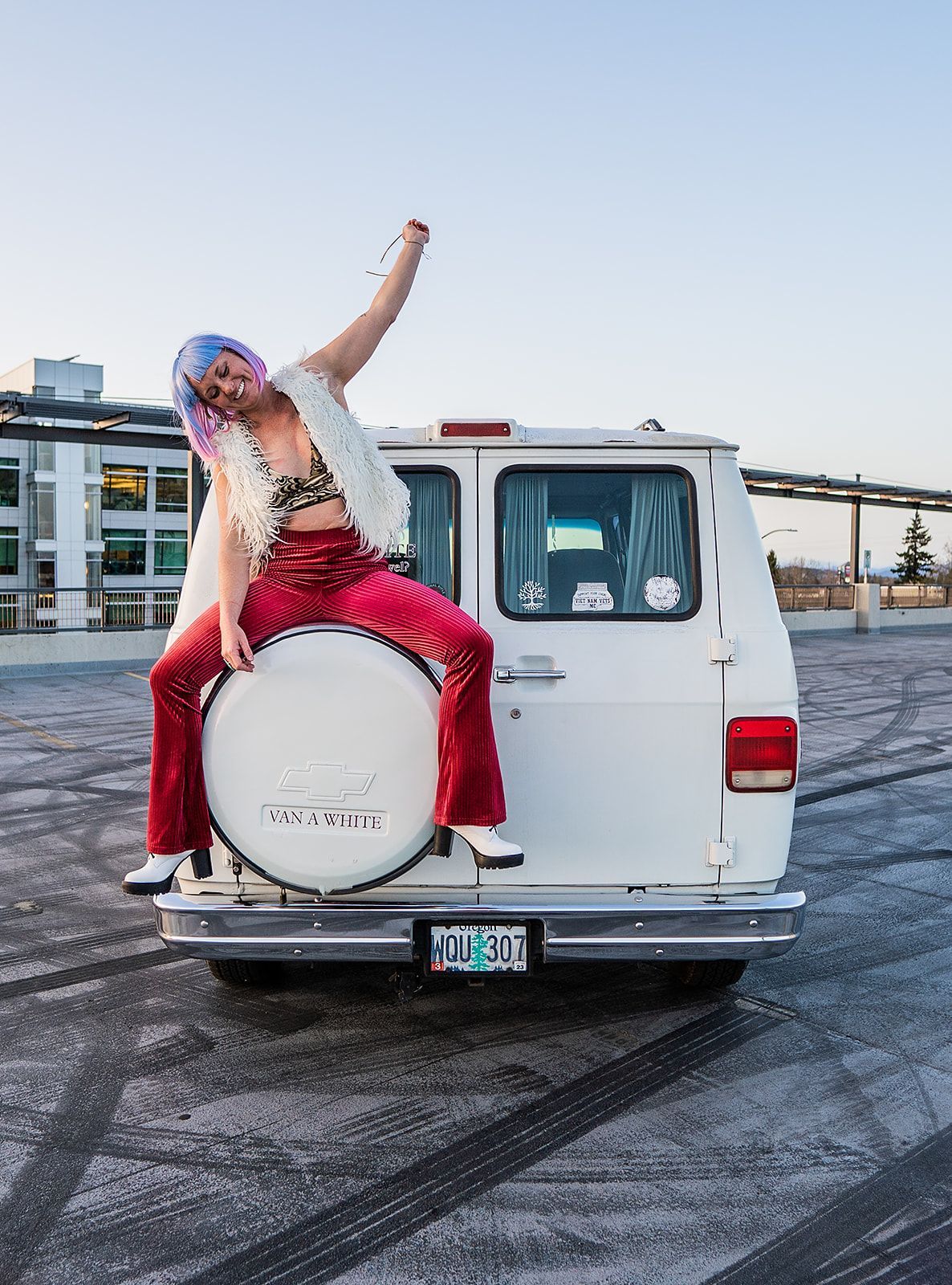 A woman is sitting on the back of a white van.