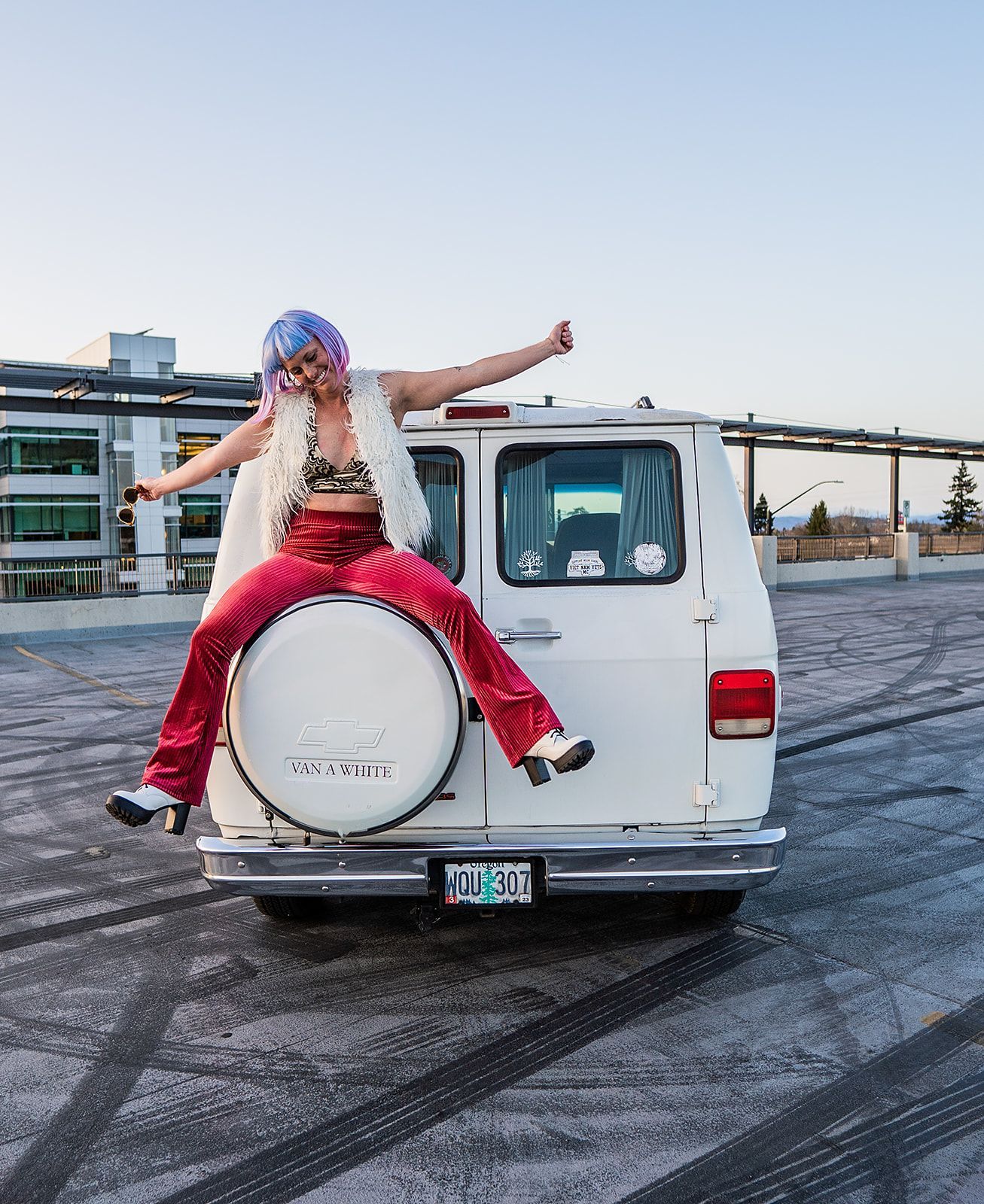 A woman is sitting on the back of a white van
