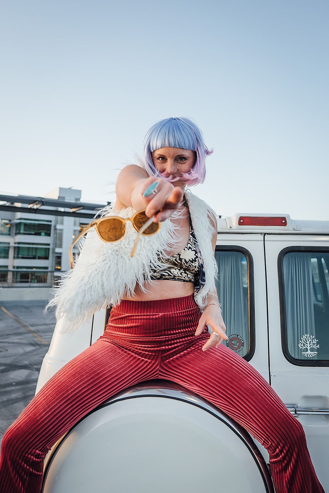 A woman is sitting on the back of a white van.