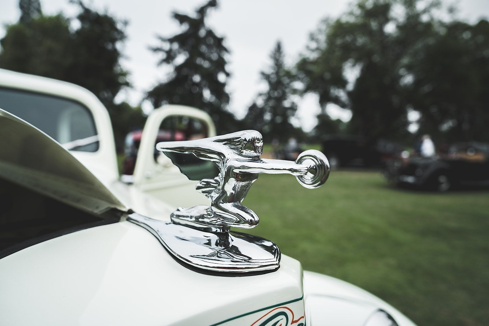A close up of a car hood ornament on a white car.