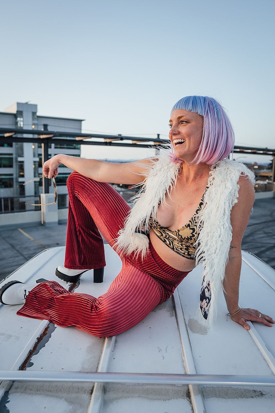 A woman with pink hair is sitting on a white roof.