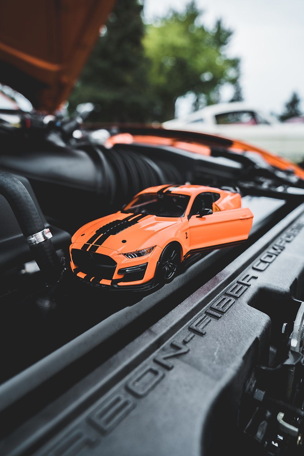 A toy car is sitting in the engine of a car.