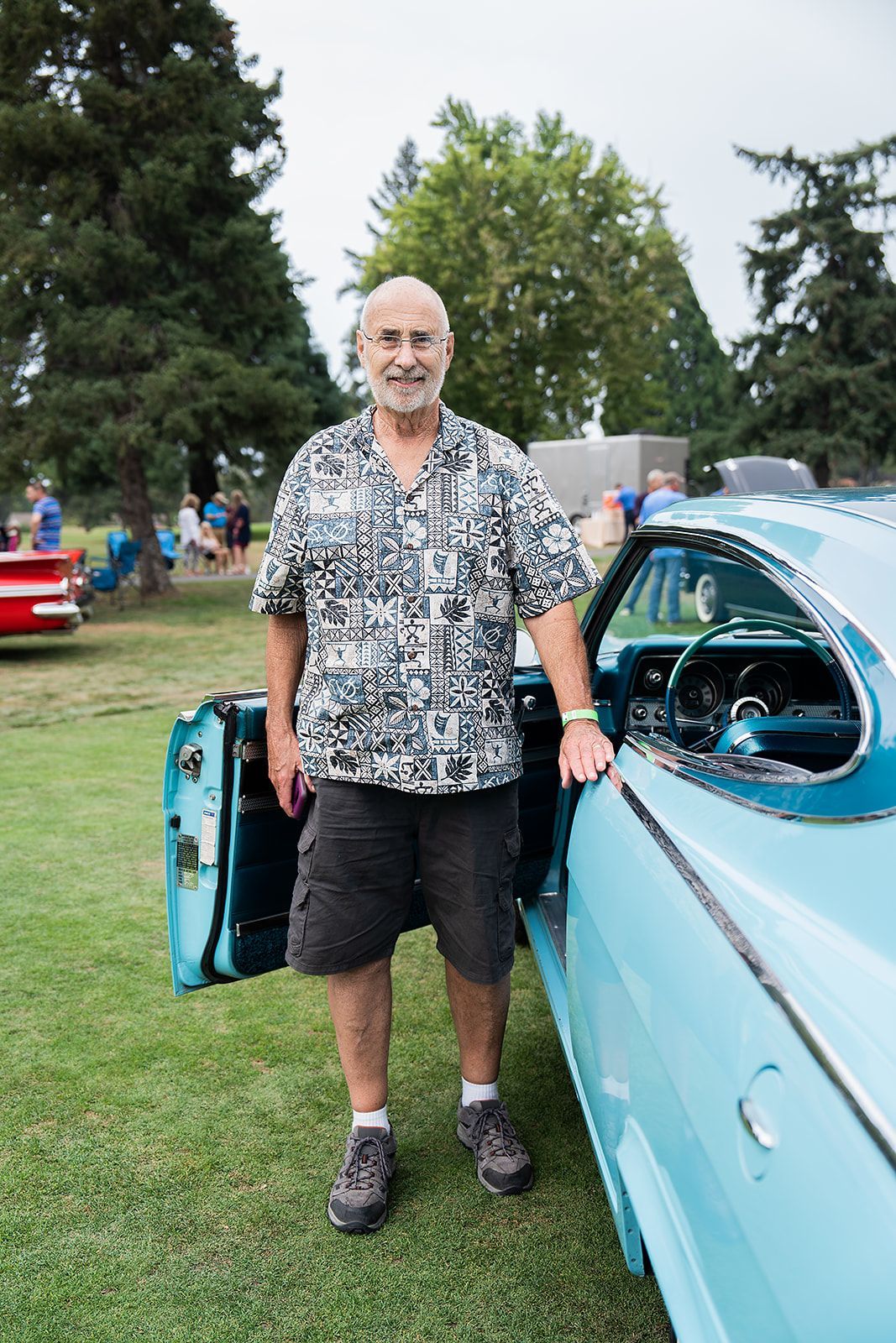 A man is standing next to a blue car with the door open.