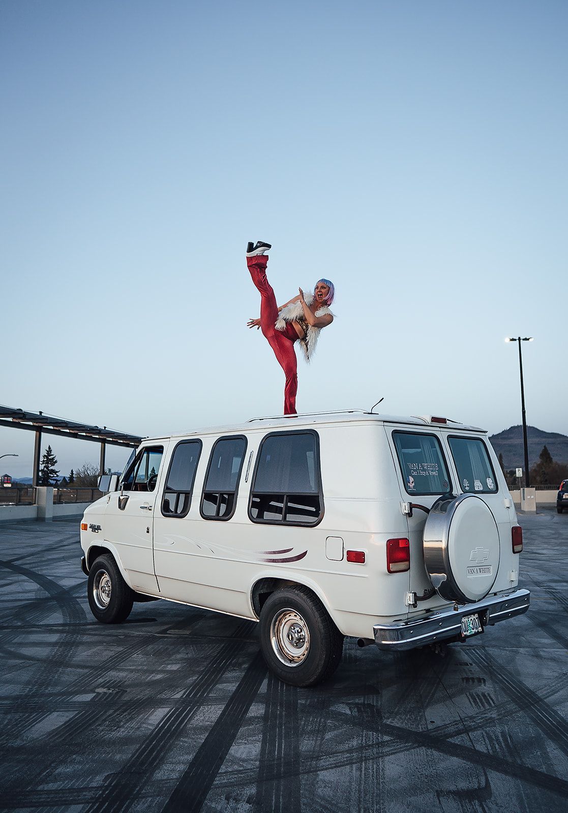 A person is doing a handstand on top of a white van