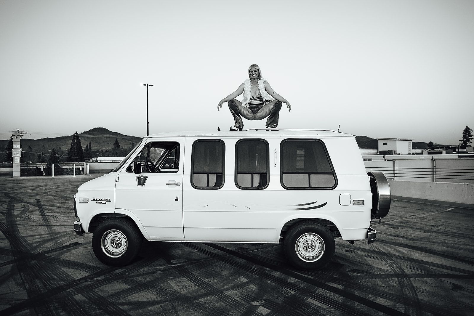 A man is squatting on top of a white van