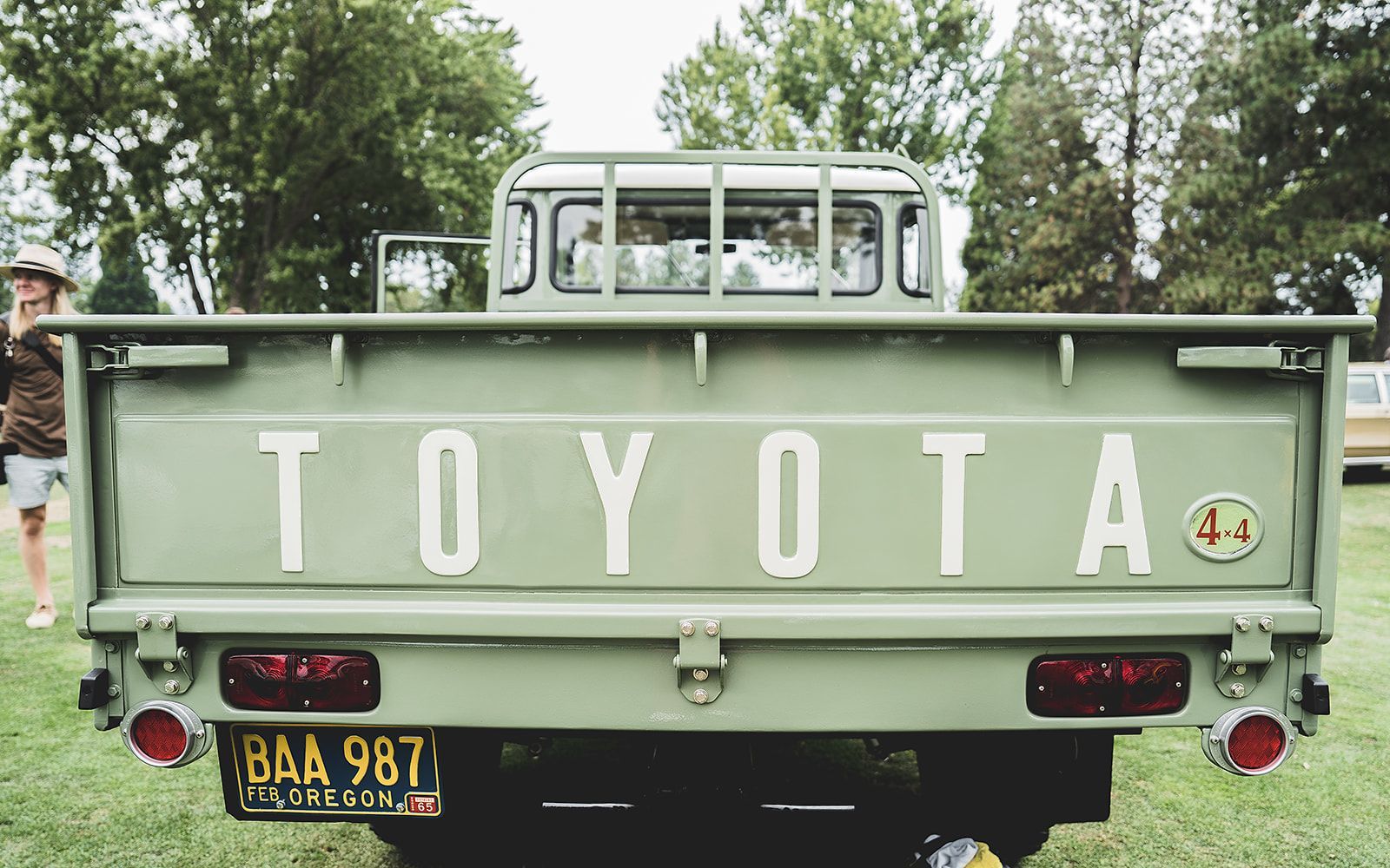 A green toyota truck is parked in a grassy field.