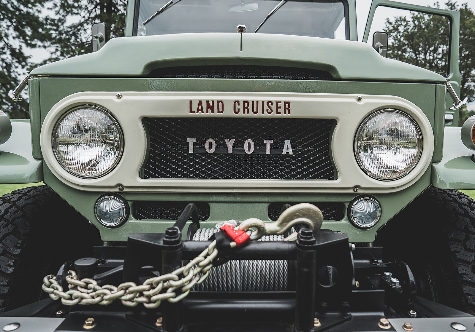 The front of a green toyota land cruiser with a winch attached to it.